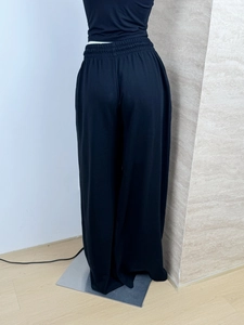 Rear view of high-waisted black wide-leg sweatpants on mannequin in indoor setting
