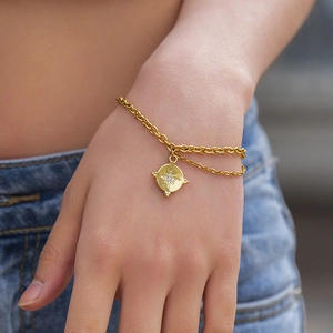 Boho layered gold bracelet featuring a double chain and crystal-set starburst coin pendant