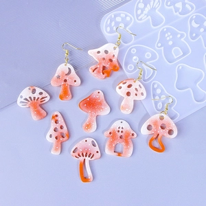DIY mushroom earring resin mold kit with orange and white spotted charms on purple background