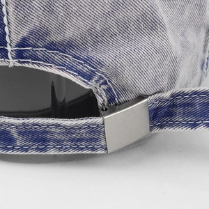 Detail of adjustable metal buckle and denim strap on blue washed cotton baseball cap