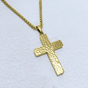 Close-up of golden cross pendant with hammered texture and matching wheat chain