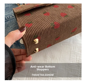 Close-up of golden protective studs on the brown corduroy strawberry embroidery bag