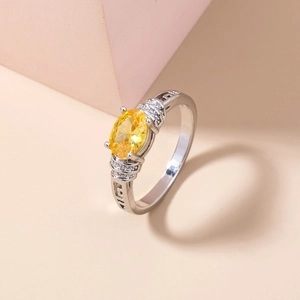 Macro detail of silver ring with oval yellow gemstone and side zircon accents