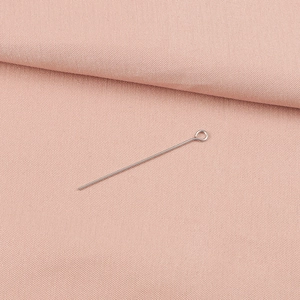 Macro detail of silver stainless steel eye pins on pink textured fabric for jewelry DIY