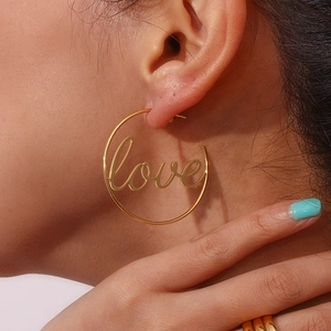 Close-up of gold circle earrings with handwritten love lettering on female model