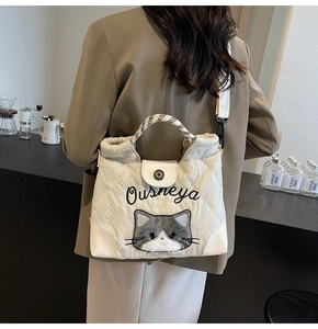 Quilted tote bag detail featuring plush cat patch and embroidered text on soft cotton fabric