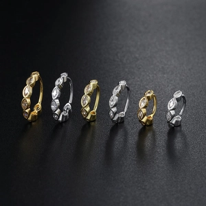 Detailed view of gold and silver geometric hoop earrings with marquise cubic zirconia
