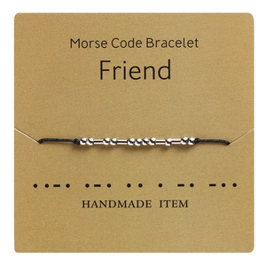 Detail view of handmade Morse code friend bracelet on kraft card with silver beads