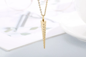 Detailed view of a gold spiral cone pendant necklace on an elegant blurred desk setup