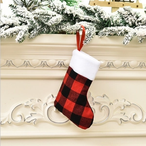 Close-up of red and black buffalo plaid Christmas stocking hanging on a snow-covered mantel