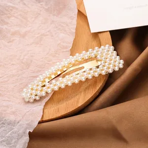 Elegant gold metal hair clip with four rows of white faux pearls on wooden tray