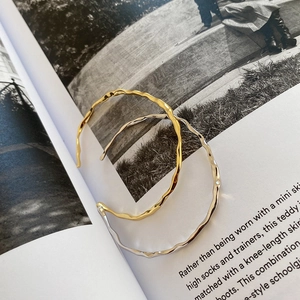 Minimalist irregular wavy hammered silver and gold open bangles on a fashion magazine