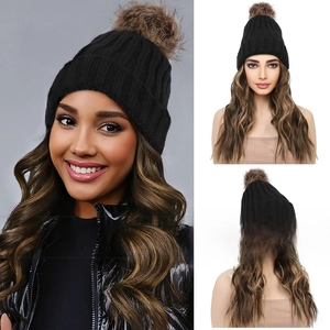 Detail of black knitted beanie with brown faux fur pom pom and long wavy synthetic hair wig