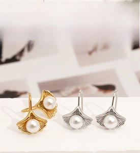 Detail of ginkgo leaf earrings in gold and silver finish with white pearl inlay