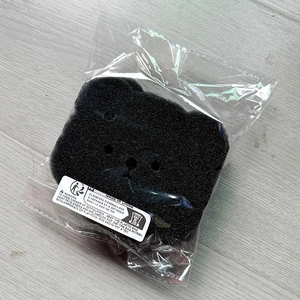 Bear-shaped laundry lint filter sponge in protective packaging with safety labels