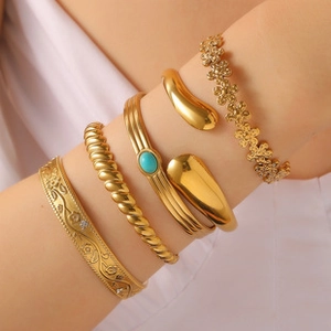 Detail of vintage gold-plated bangle set featuring turquoise stones and floral engravings