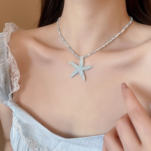 Detail of beaded necklace featuring blue and white seed beads and a resin starfish pendant