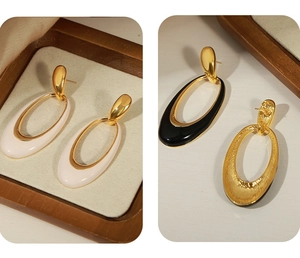 Detailed view of French vintage enamel oval earrings in cream white and deep black colors