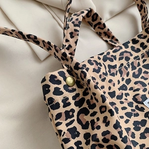Close-up of leopard print canvas tote bag showing texture and bronze metal snap closure