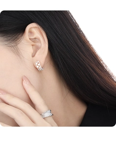 Macro shot of silver hollow-out earrings and textured ring worn by a female model