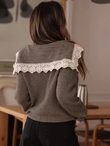 Dettaglio del colletto in pizzo bianco su cardigan in maglia marrone con trama pregiata