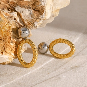Detail of mixed-metal earrings with silver spheres and golden rope textured hoops