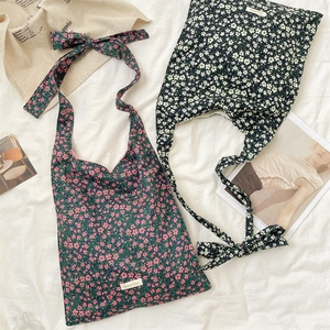 Détail de sacs bandoulière à fleurs avec bretelles nouables sur fond de tissu blanc texturé