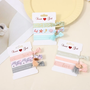 Three sets of elastic knotted hair ties with charms and floral prints on card display