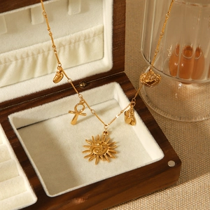 Golden stainless steel necklace with sun and shell charms in a wooden jewelry box