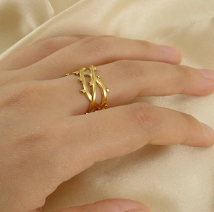 Detailed view of an adjustable gold-plated branch ring on a silk background