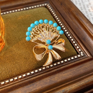 Macro view of vintage fan-shaped brooch with turquoise beads and rhinestones on velvet