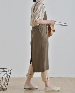 Detail of olive green washed linen apron dress featuring a long cross-back minimalist design