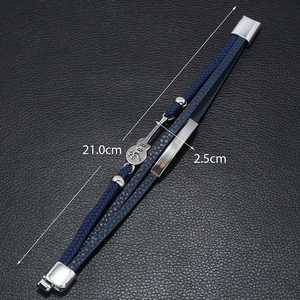 Detail of blue braided leather bracelet featuring a silver guitar charm and musical notes