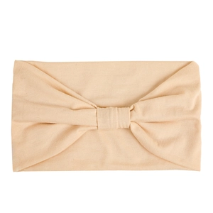 Detail view of the beige elastic yoga headband featuring a central cross-knot design