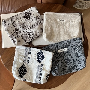 Linen makeup pouch set with four vintage floral patterns and fabric labels on wooden table