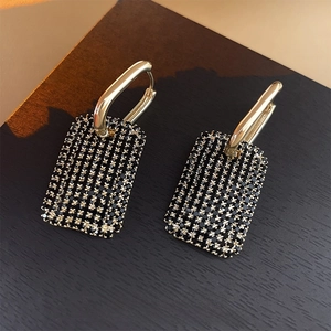 Boucles d'oreilles carrées dorées élégantes avec strass noirs sur fond sombre
