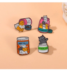 Detail of four cat-themed enamel pins featuring happy pill bottle designs in metal