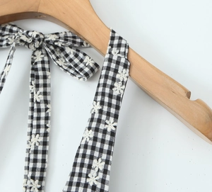 Detail of black and white plaid dress strap with floral embroidery and bow knot