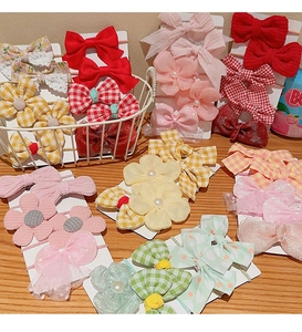 Detailed assortment of colorful bow hair clips and elastic ties for girls on a wooden surface