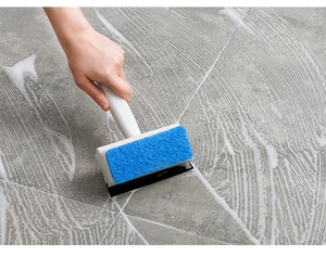 Detail showing 2-in-1 cleaning brush with sponge and squeegee on bathroom wall tiles