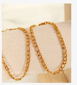 Detailed close-up of a high-polish gold Figaro chain bracelet on a jewelry roll
