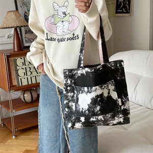 Dettaglio della borsa tote in tela tie-dye con etichetta laterale e tasca frontale