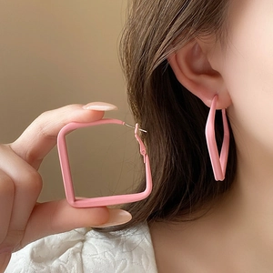 Detail of pink square geometric drop earrings with matte finish on a female model