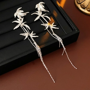 Detailed shot of silver bamboo leaf tassel earrings on a black jewelry display tray