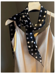Close-up of black and white polka dot chiffon scarf necklace with fabric flower detail.