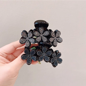 Dettaglio di una pinza per capelli nera con sei eleganti decorazioni floreali in strass