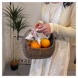 Detail of woven rattan basket bag with decorative pink scarf and fruit props inside