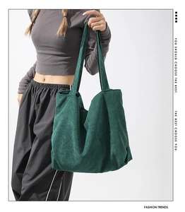 Detail of dark green corduroy tote bag featuring a wide shoulder strap and soft texture