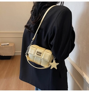 Détail d'un sac bandoulière tissé jaune clair avec breloque étoile et chaîne métal