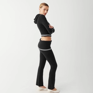 Side view of black knit two-piece set featuring cropped hoodie and flared pants with white stripes